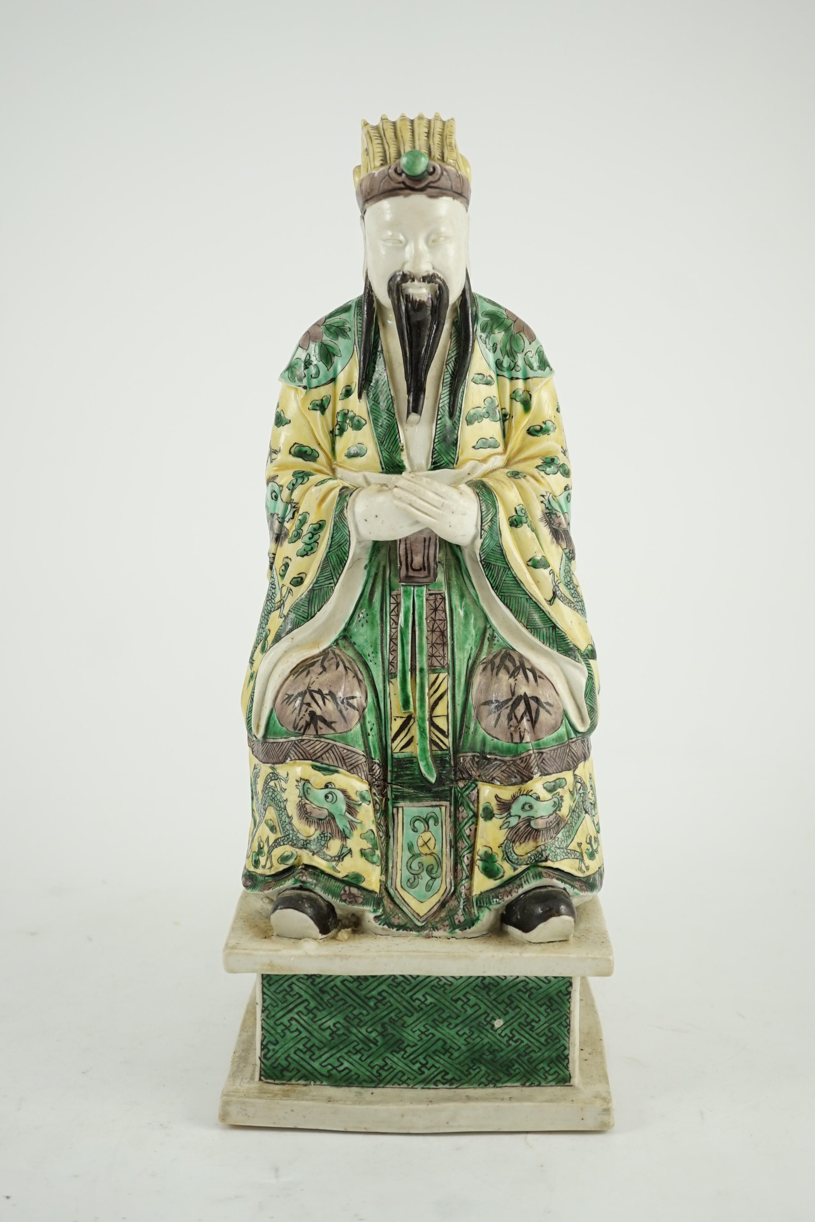 A Chinese enamelled biscuit figure of a seated court official, Kangxi period, 31.5cm high, small losses